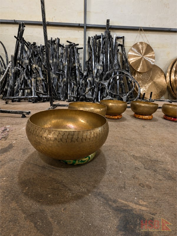 Handmade singing bowl beside traditional forming and finishing tools in a Nepal workshop